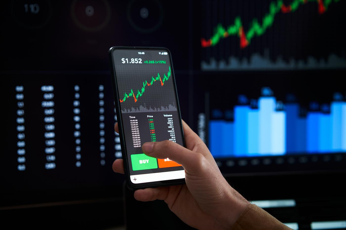 A hand holding a phone showing a trading app