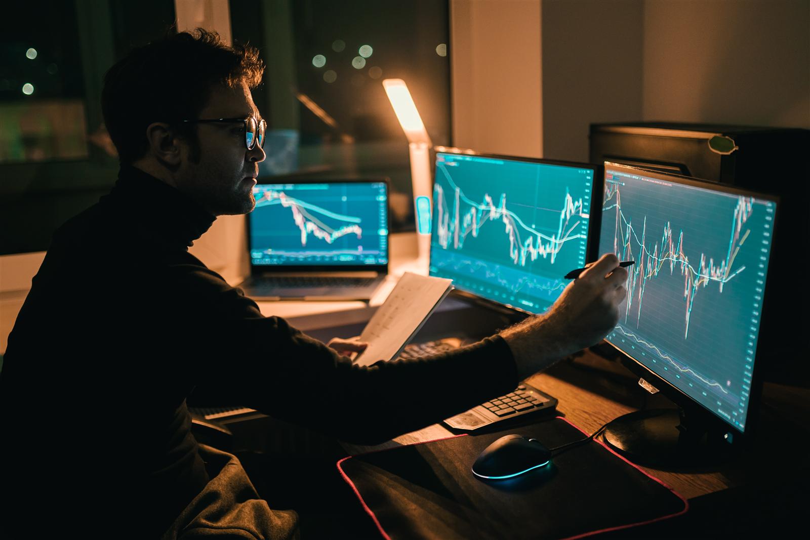 A trader reviewing currency charts on several screens
